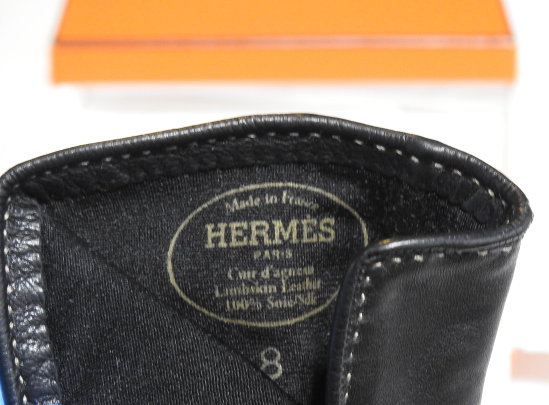 Close up picture of the Hermes brand appearing in black lambskin leather gloves for sale. Ladies size 8