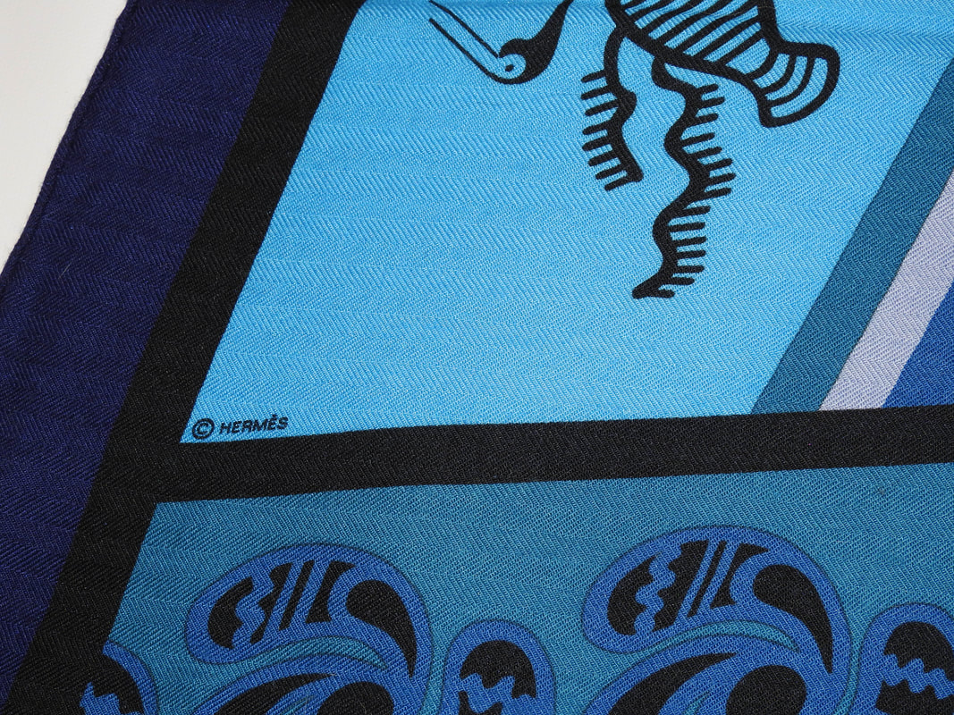 Close up Picture of copyright in used Hermes 140cm silk and cashmere s hawl for sale Geometrie Cretoise, a celebration of Cretian art in various shades of blue