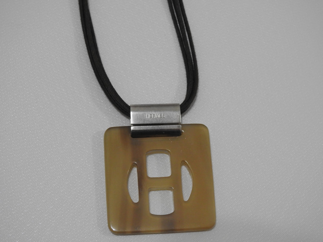 Picture of Hermes buffalo horn necklace. H pendant on leather cord.