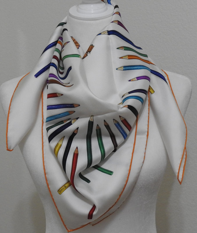 Picture of used Hermes 90cm silk scarf for sale. A Vos Crayons by Leigh Cook, white with orange contrast hem. Tied in cowboy knot