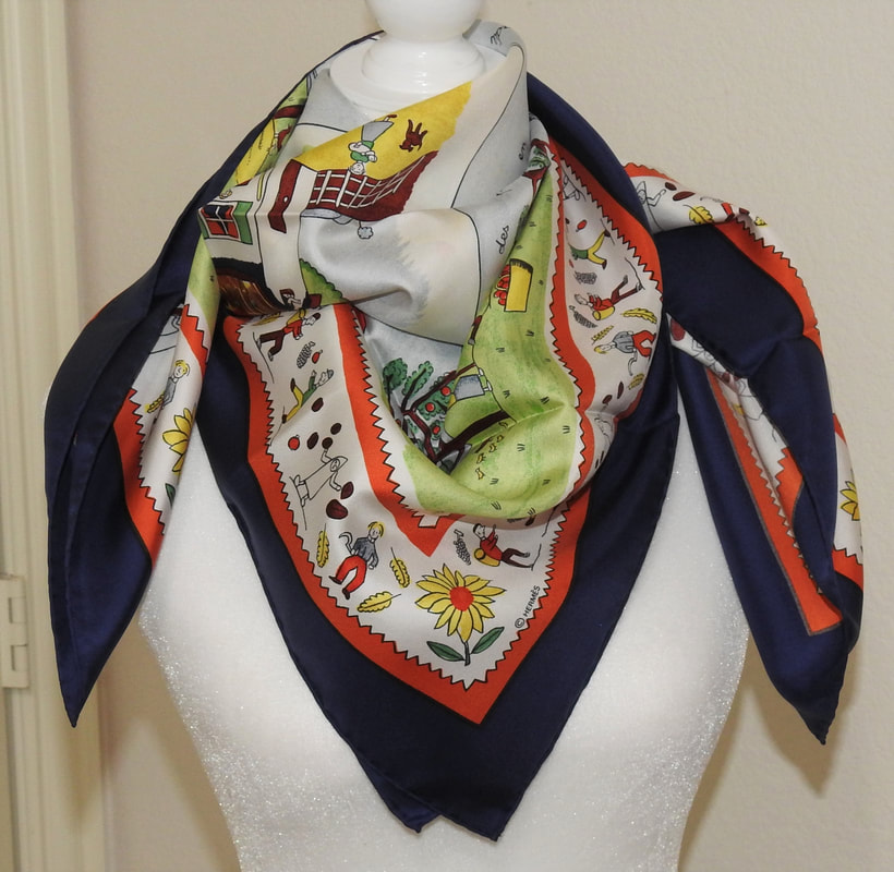 Picture of Retour a la Terre, a used Hermes 90cm silk scarf for sale. This blue, red and green colorway is tied in a cowboy knot