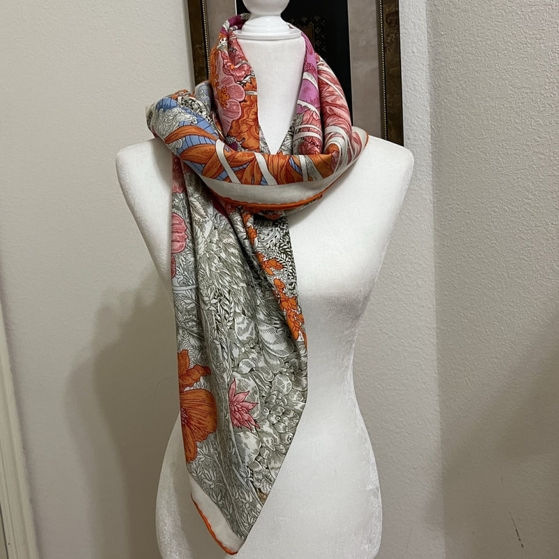 Picture of used Hermes 140cm cashmere s shawl for sale. Retour a la Nature by Octave Marsal and Theo de Gueltzl. Floral design in pink and blue and orange, shown here in a loose knot