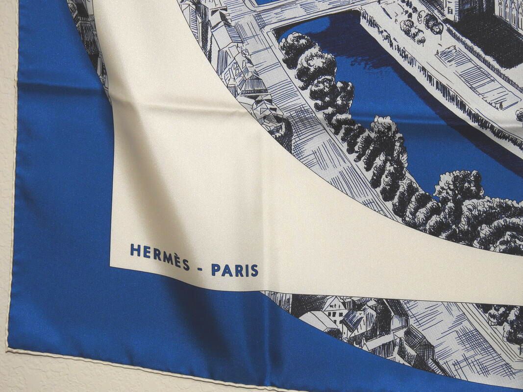 Close up picture of the Hermes brand appearing in a used Hermes 90cm silk scarf Regarde Paris