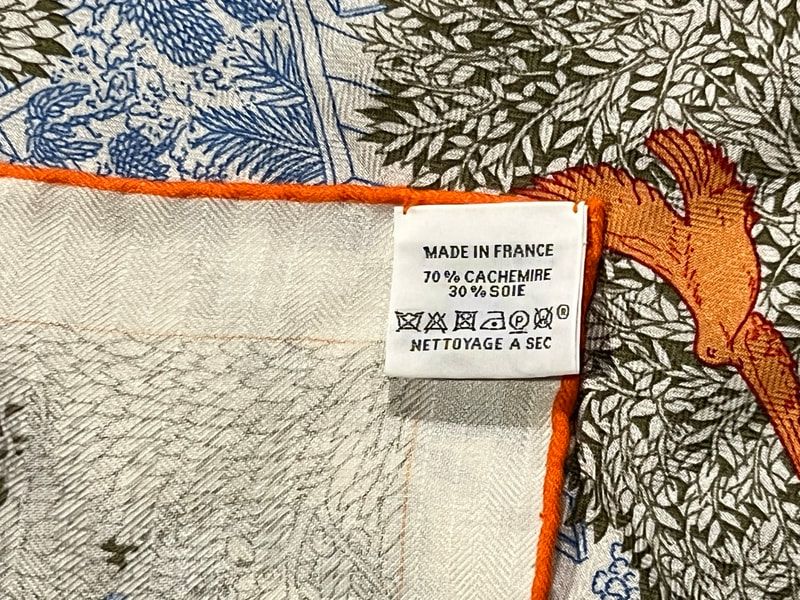 Picture of the caretag attached to Retour a la Nature, a blue and orange 140cm Hermes silk cashmere shawl
